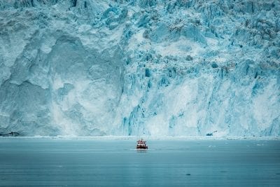 Ein kleines Passagierboot vor der riesigen Gletscherwand am Eqi-Gletscher in Grönland - Fotograf: Mads Pihl - Visit Greenland