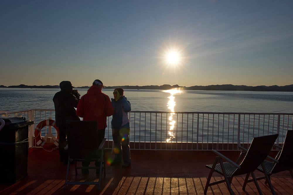 Tourist On The Upper Deck Of Sarfaq Ittuk Under The Midnight Sun In Greenland